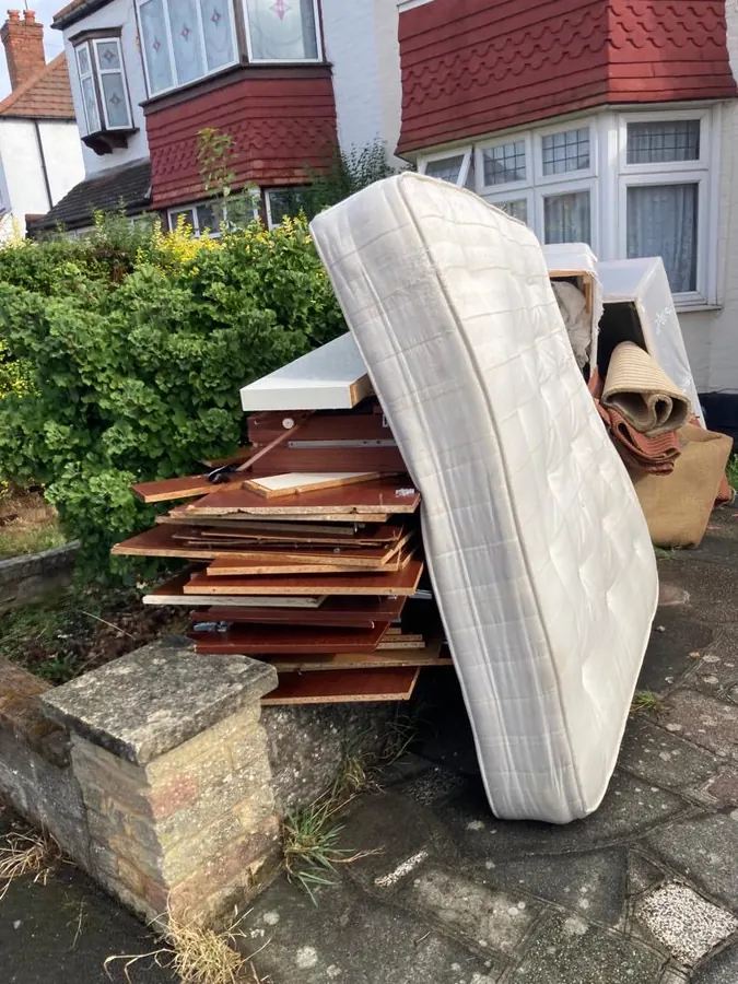 Mattress and old furniture panels in a front garden before collection