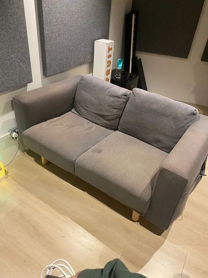 Grey two-seater sofa ready for collection in a living room
